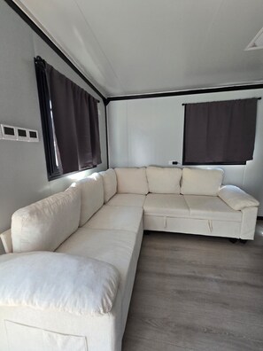 Un interior modern amb un sofà modular, finestres grans amb cortines i un disseny minimalista.