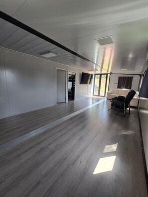 Una habitación amplia con un ventanal grande, un ventilador de techo y una silla negra.