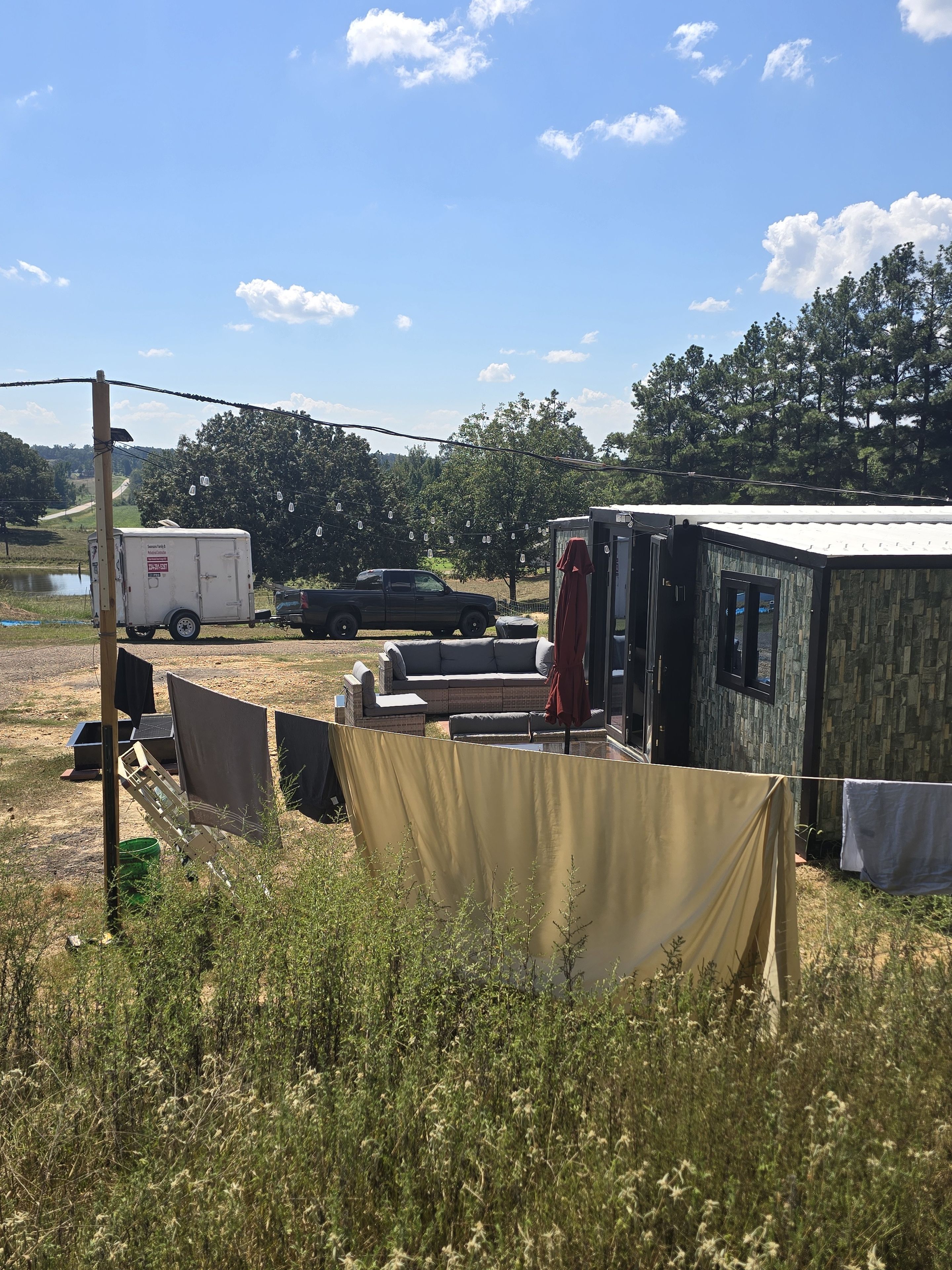 A campsite with a portable toilet, a trailer, and a vehicle.