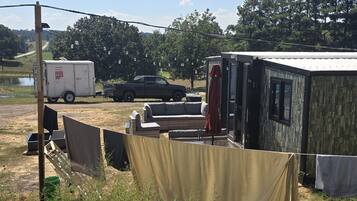 A campsite with a portable toilet, a trailer, and a vehicle.