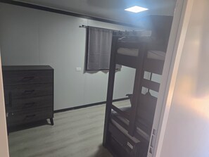 Una habitación con una litera, un aparador y un interruptor de luz en la pared.