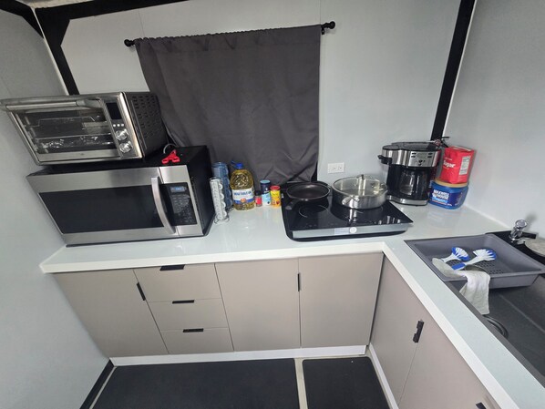 Una kitchenette compacta equipada con microondas, tostadora y cafetera.