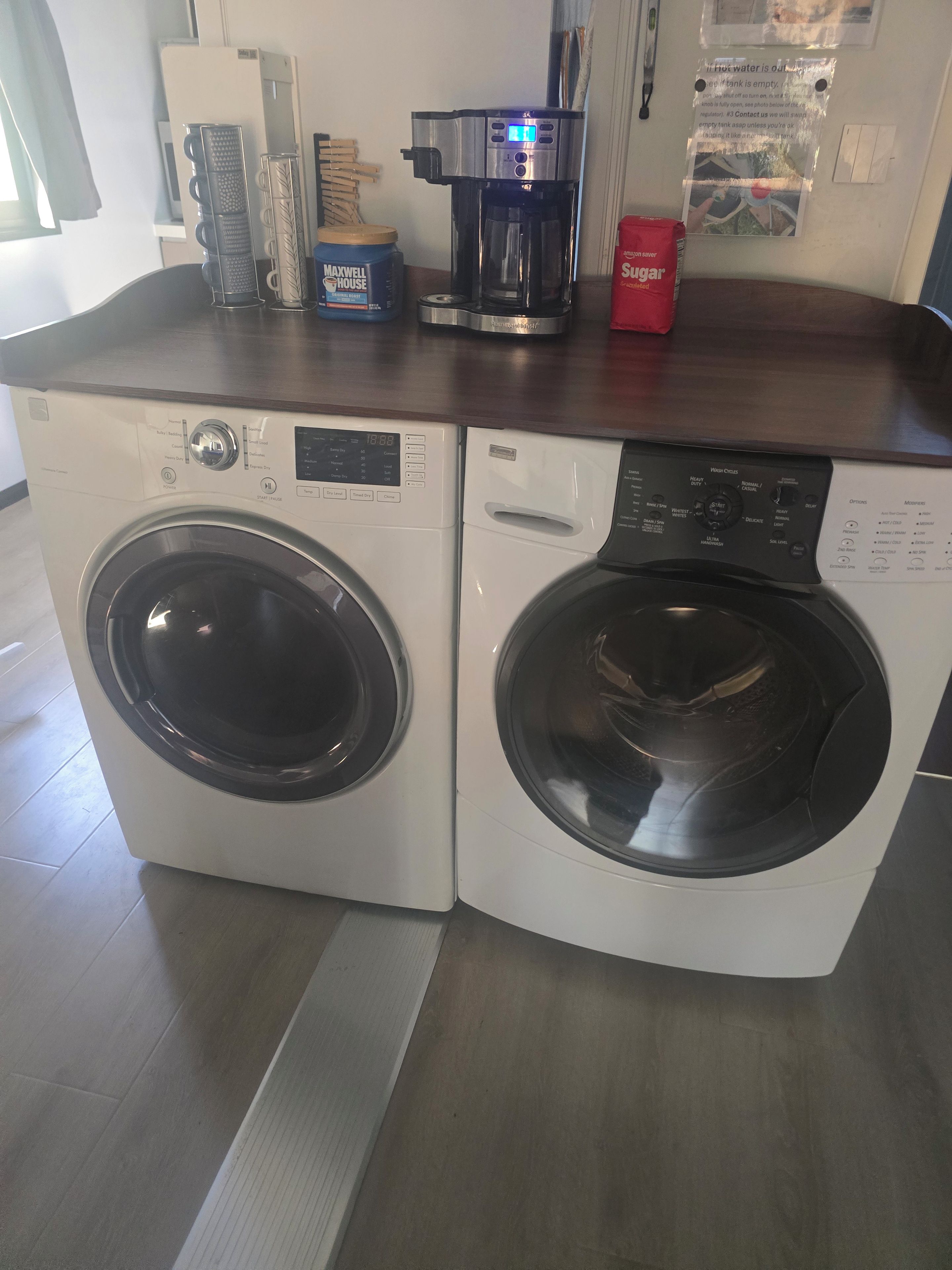 A laundry area with two front-loading washing machines and a coffee maker on the counter.