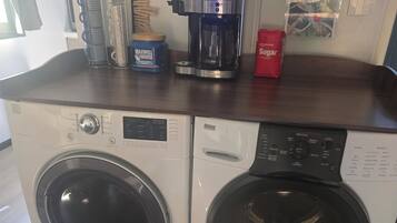A laundry area with two front-loading washing machines and a coffee maker on the counter.