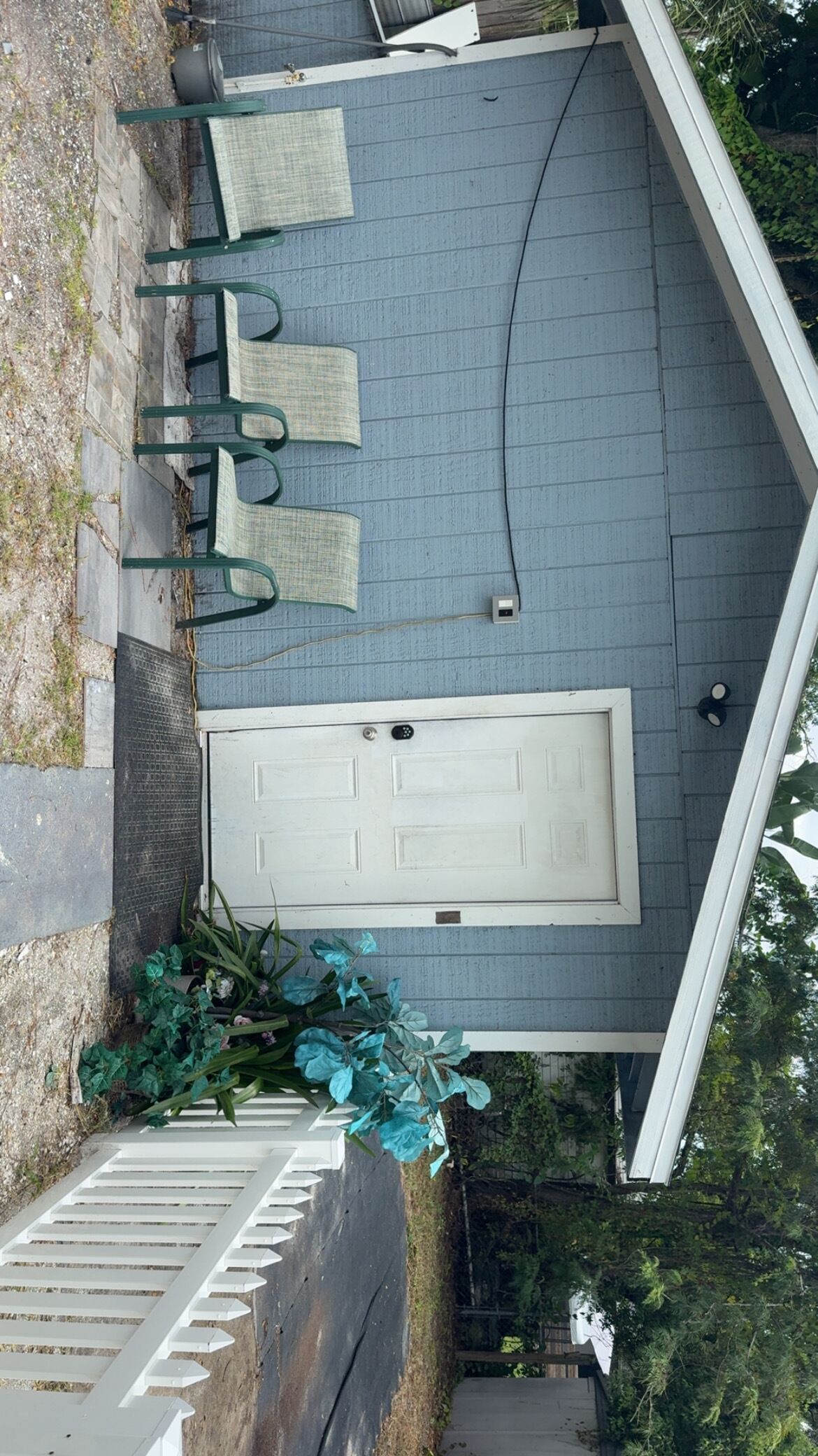 Un patio cubierto con puerta, mobiliario exterior y un pequeño jardín.