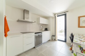 A modern kitchen with white cabinets, a stainless steel range hood, and a dishwasher. - Calafell Seaside Escape (Calafell)