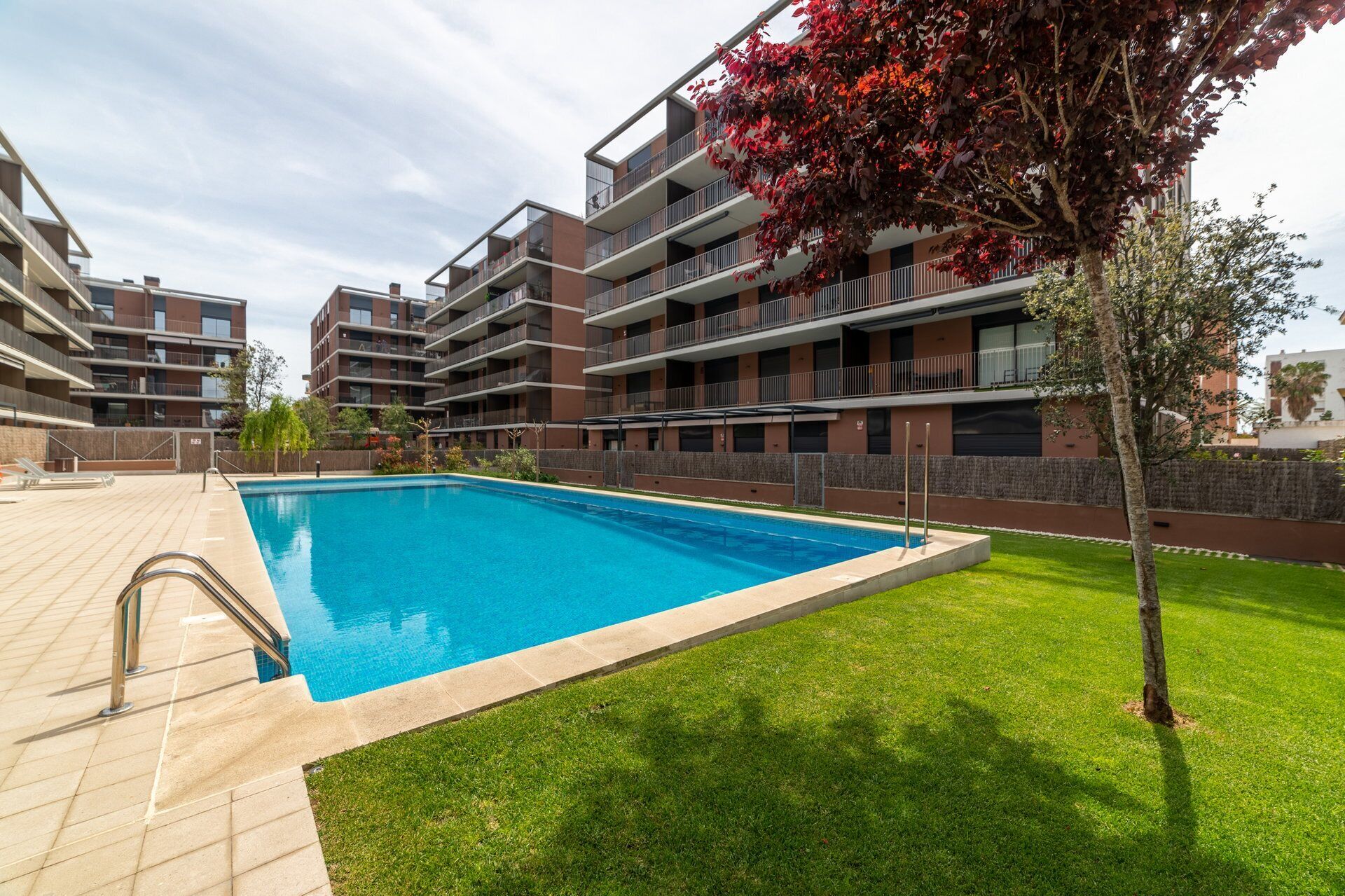 Un moderno edificio de apartamentos con piscina y césped bien cuidado.