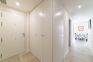 A hallway with white doors, a dining area with a table and chairs, and a framed picture on the wall. - Calafell Seaside Escape (Calafell)