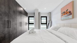Ein modernes Schlafzimmer mit einem großen Bett, einem Kleiderschrank und einem Bild an der Wand.