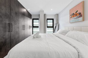 Ein modernes Schlafzimmer mit einem großen Bett, einem Kleiderschrank und einem Bild an der Wand.