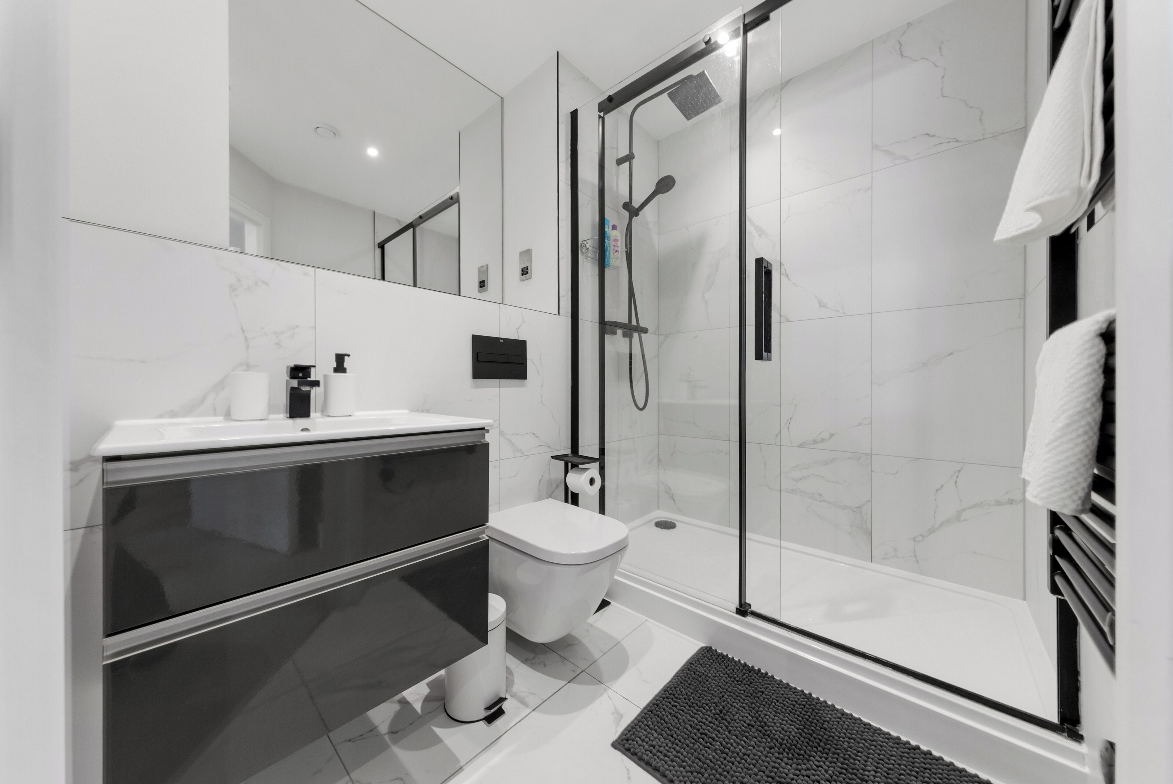 A modern bathroom with a glass-enclosed shower, a toilet, and a vanity with a mirror.