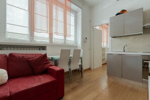 A modern kitchen with a built-in oven, a dining area with a table and chairs, and a red sofa. - A comfortable 42 sqm apartment, ideal for 3 people, located on the raised ground floor of a building (steps required for access).The apartment is strategically located, 750 meters from the “Porta Romana” stop on the M3 (Yellow) metro line, which take (Milan)