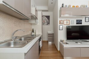 A modern kitchen with a stainless steel sink, a built-in oven, and a flat-screen TV. - A comfortable 42 sqm apartment, ideal for 3 people, located on the raised ground floor of a building (steps required for access).The apartment is strategically located, 750 meters from the “Porta Romana” stop on the M3 (Yellow) metro line, which take (Milan)
