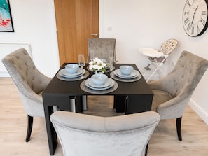 A dining table set with plates, glasses, and a vase of flowers. - 4 Bed House in Kent | Free Parking | Sleeps 8 | Long Stays (Sittingbourne)