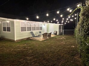 A small house with a covered patio area, string lights, and outdoor furniture. - Welcome to The Hickory Cottage, a charming coastal retreat in Bay St. Louis (Bay St. Louis)