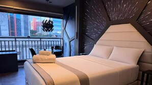 A modern bedroom with a large bed, a view of the city through a balcony, and a unique wall design. - Themed Studio | Liberdade Metro Station (São Paulo)
