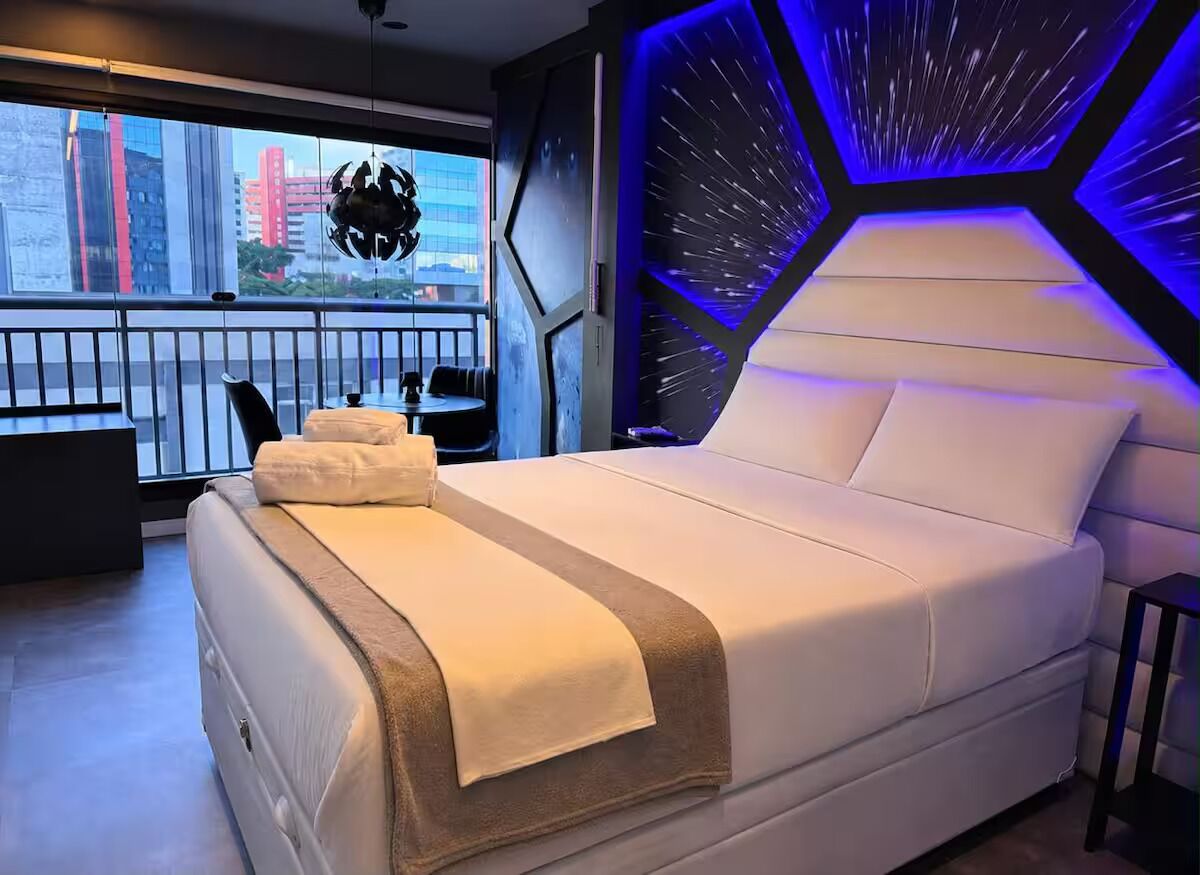 Ein modernes Schlafzimmer mit einem großen Bett, Blick auf die Stadt von einem Balkon und einem einzigartigen geometrischen Wanddesign.