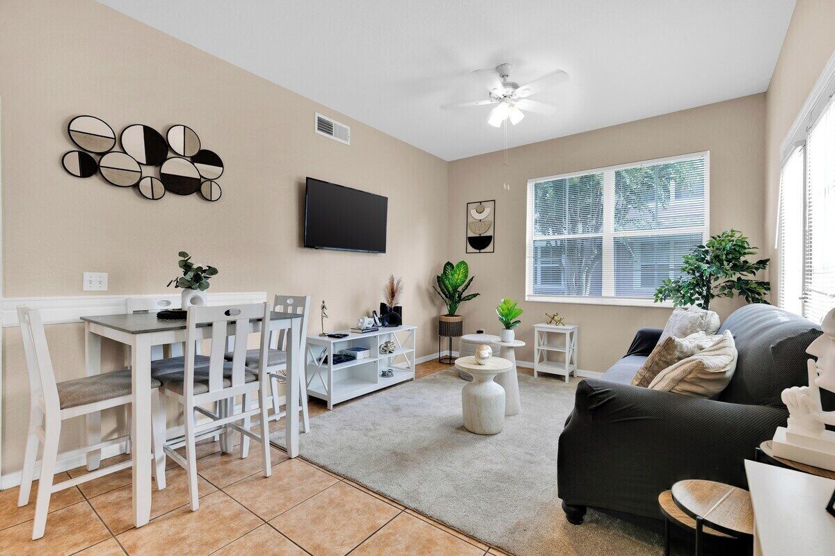 Un salon comprenant un canapé, un téléviseur, une table à manger, des chaises et un ventilateur de plafond.