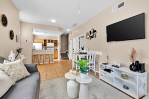 Ein modernes Wohnzimmer mit grauem Sofa, einem Couchtisch und einem an der Wand befestigten Fernseher.