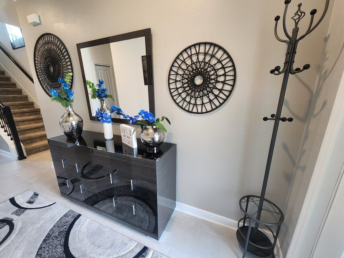 A modern bathroom with a black vanity, a large mirror, decorative wall art, and a coat rack.