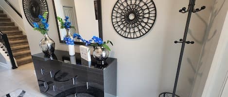 A modern bathroom with a black vanity, a large mirror, decorative wall art, and a coat rack.