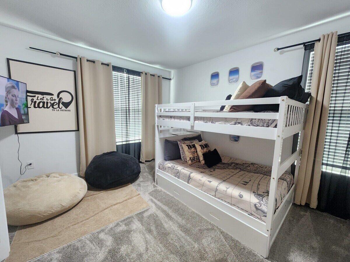 A bunk bed room with a television, curtains, and a framed picture on the wall.