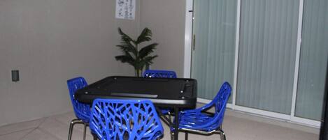 Un coin repas avec une table et quatre chaises bleues, une plante en pot et une affiche accrochée au mur.