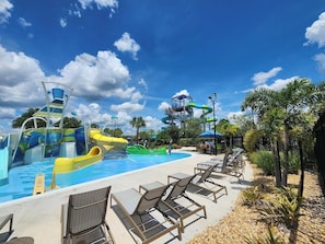 Ein Wasserpark mit Rutschen und einem Poolbereich, umgeben von Palmen und Liegestühlen.