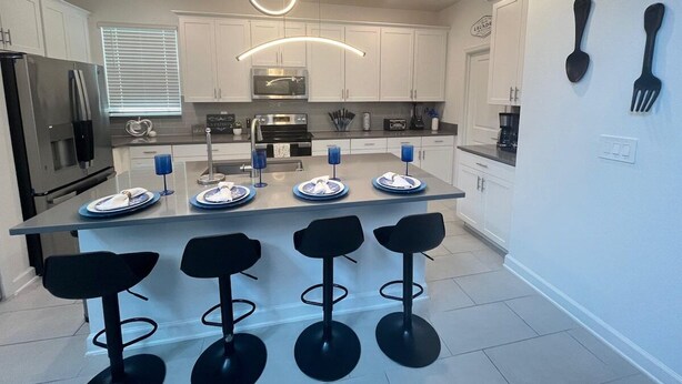Una cocina moderna con una isla central, taburetes de bar y electrodomésticos integrados.