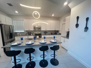 A modern kitchen with a central island, bar stools, and built-in appliances. - Villa w/ Private Pool, Near Disney - Champions (Davenport)