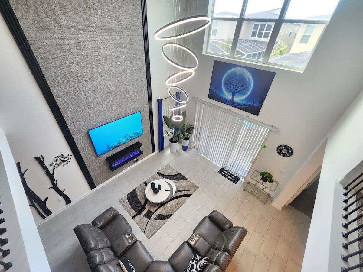 A modern living room with a flat-screen TV, leather sofas, a coffee table, and a spiral light fixture.