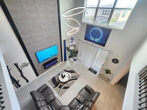 A modern living room with a flat-screen TV, leather sofas, a coffee table, and a spiral light fixture. - Villa w/ Private Pool, Near Disney - Champions (Davenport)