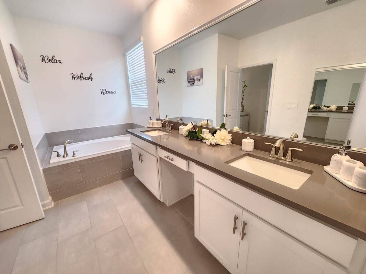 A modern bathroom with a bathtub, two sinks, and a large mirror.