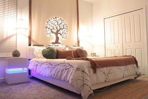 Ein Schlafzimmer mit einem Bett, Nachttischlampen, einer an der Wand befestigten Baumdekoration und einem Kleiderschrank.