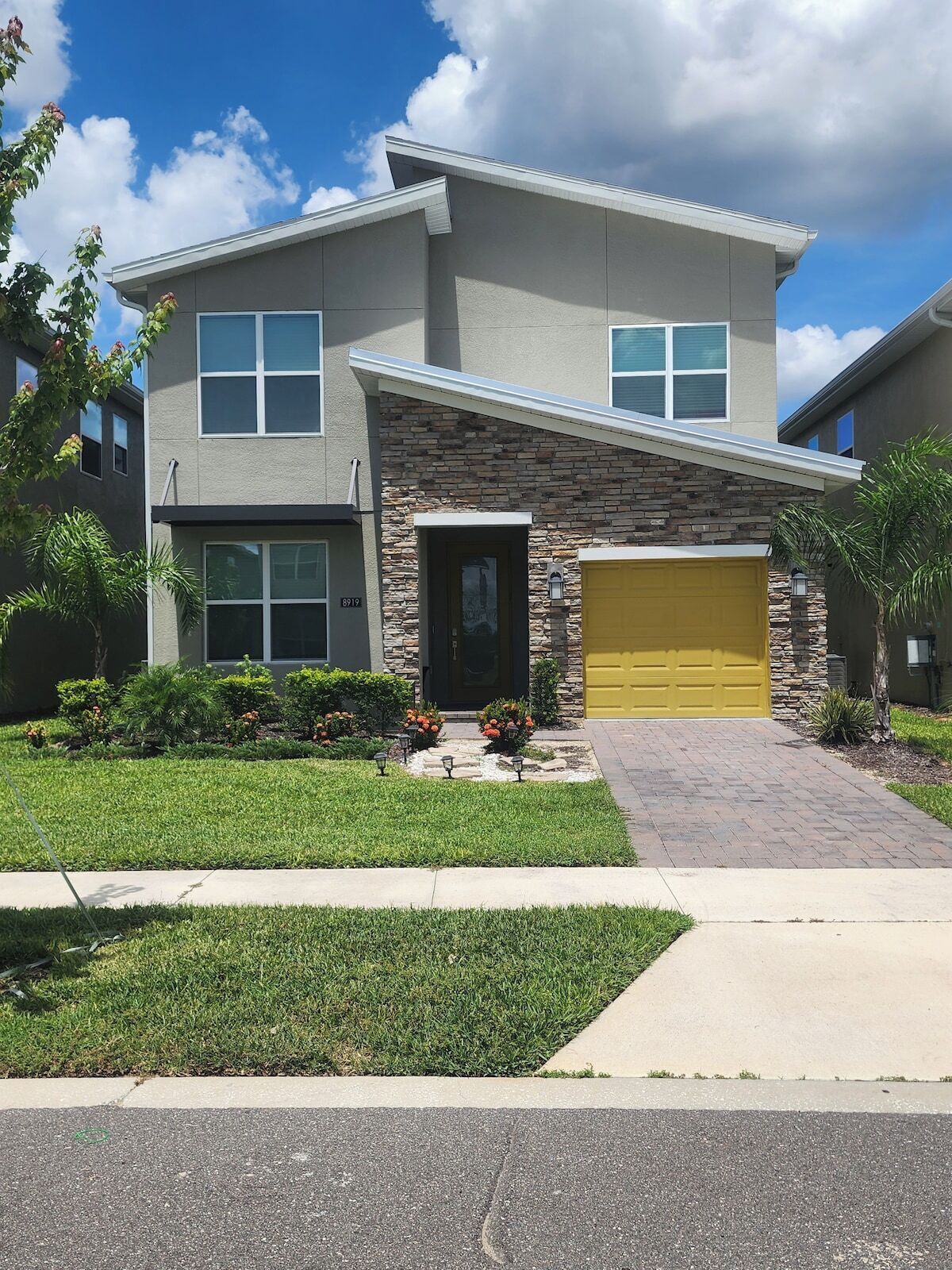 A two-story house with a stone facade, a front garage, and a well-maintained lawn.