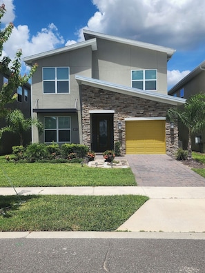 A two-story house with a stone facade, a front garage, and a well-maintained lawn. - Villa w/ Private Pool, Near Disney - Champions (Davenport)