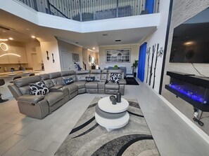 Ein modernes Wohnzimmer mit Ecksofa, rundem Couchtisch und Kamin.