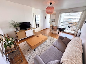 Ein modernes Wohnzimmer mit Sofa, Couchtisch, Fernseher und Essbereich.