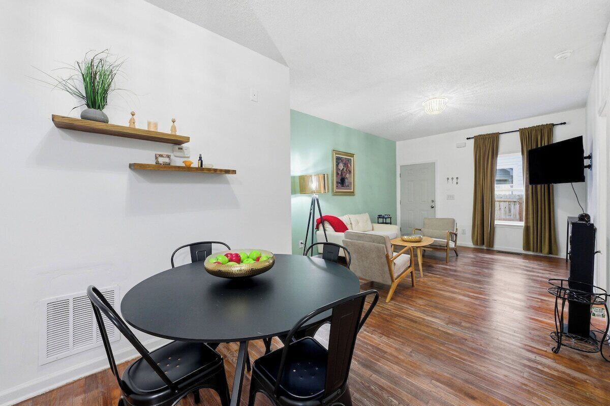 Een eethoek met een ronde tafel en stoelen, een fruitschaal en een plant op een plank.