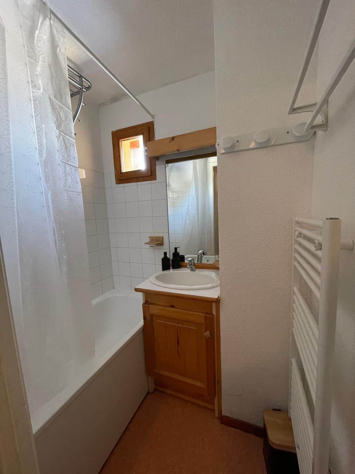 Een kleine badkamer met een douche, wastafel en spiegel.