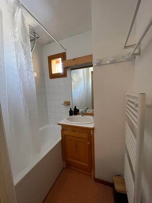 Ein kleines Badezimmer mit Dusche, Waschbecken und Spiegel.
