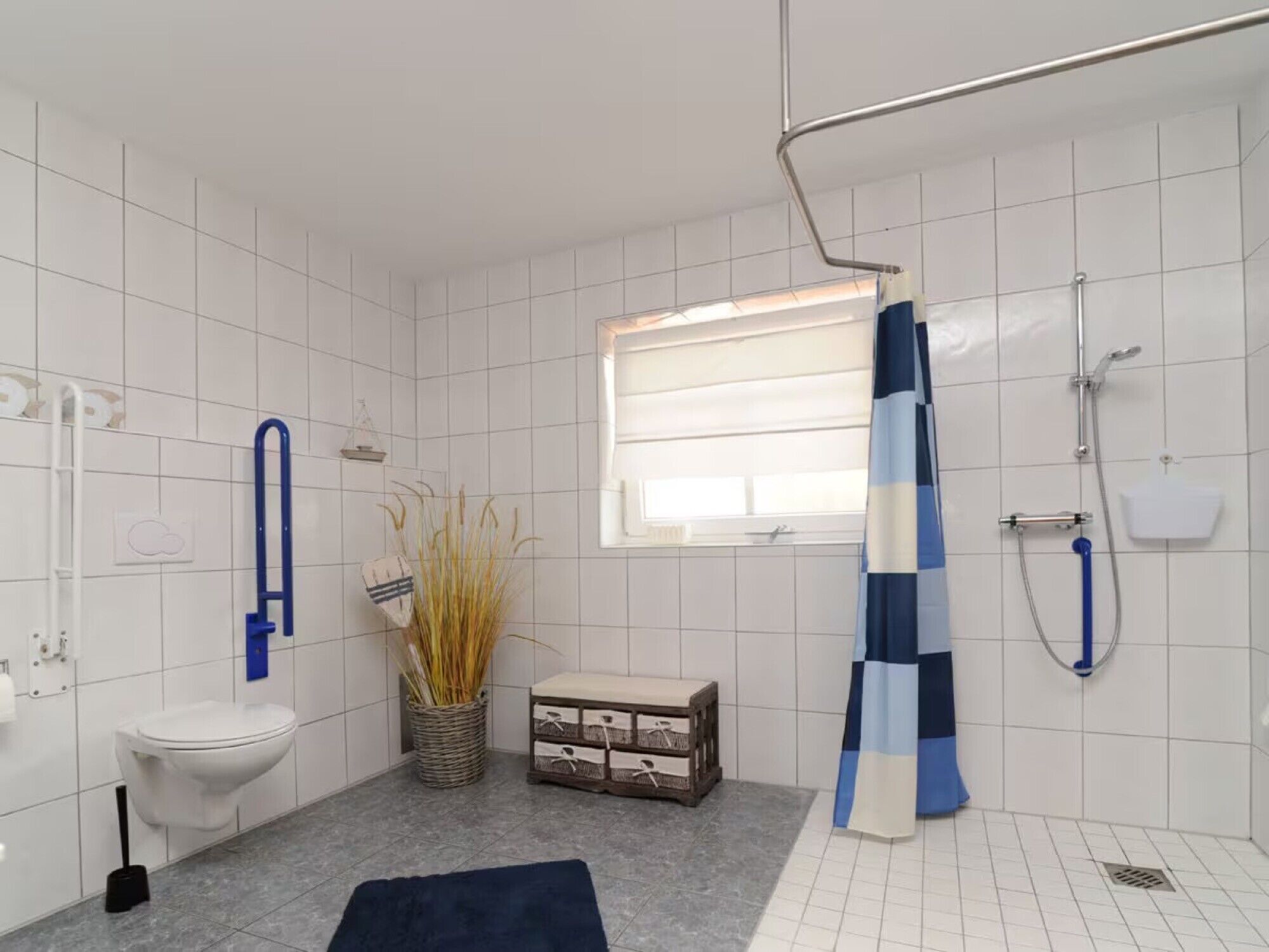 Ein Badezimmer mit Toilette, Dusche, einem Fenster und einem blauen und weißen Duschvorhang.