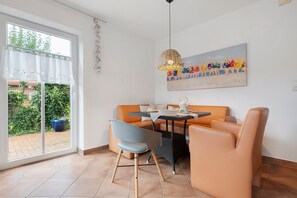 A dining area with a table, chairs, and a painting on the wall.