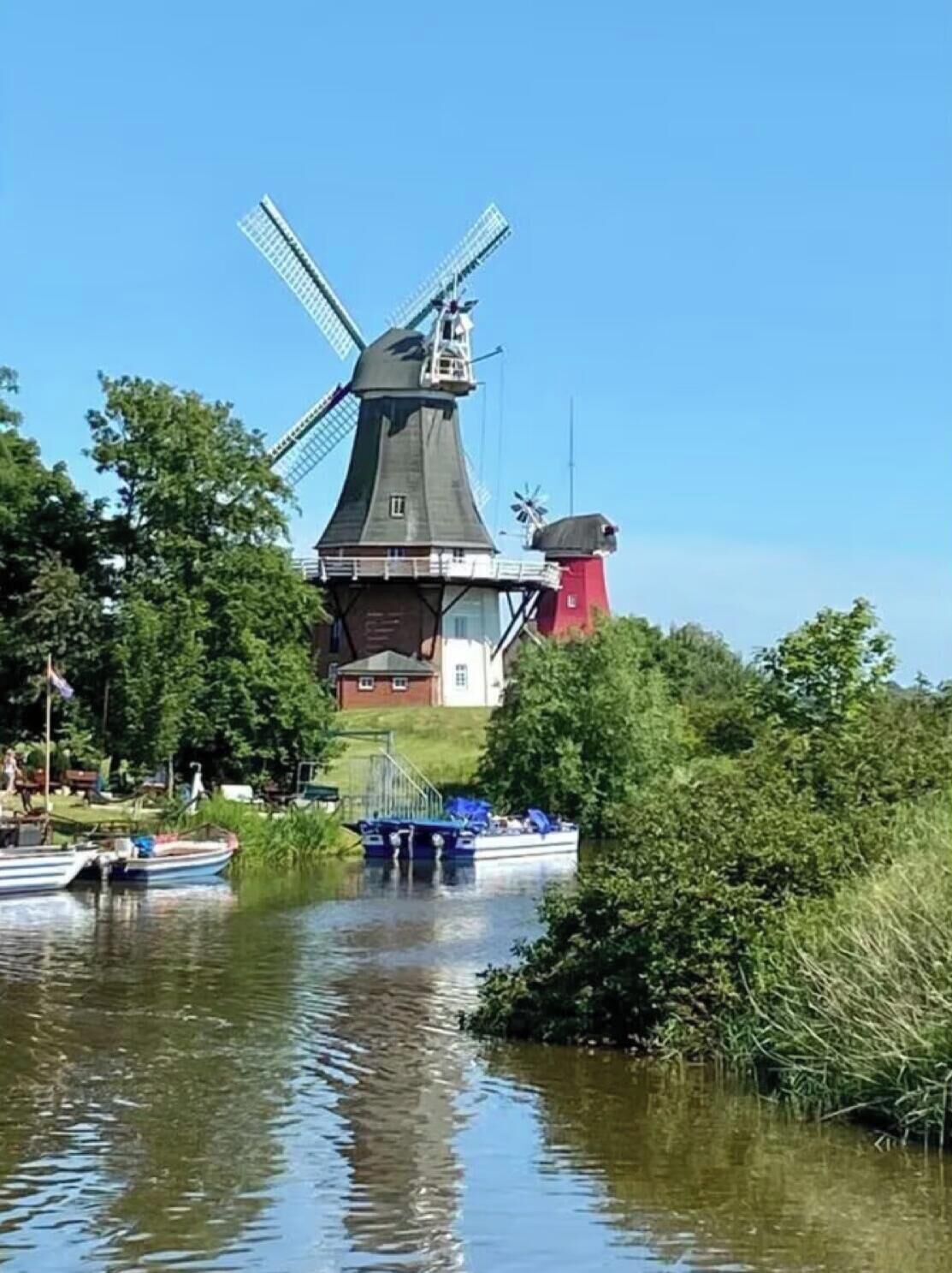 Eine Windmühle mit einem Wasserweg im Vordergrund.