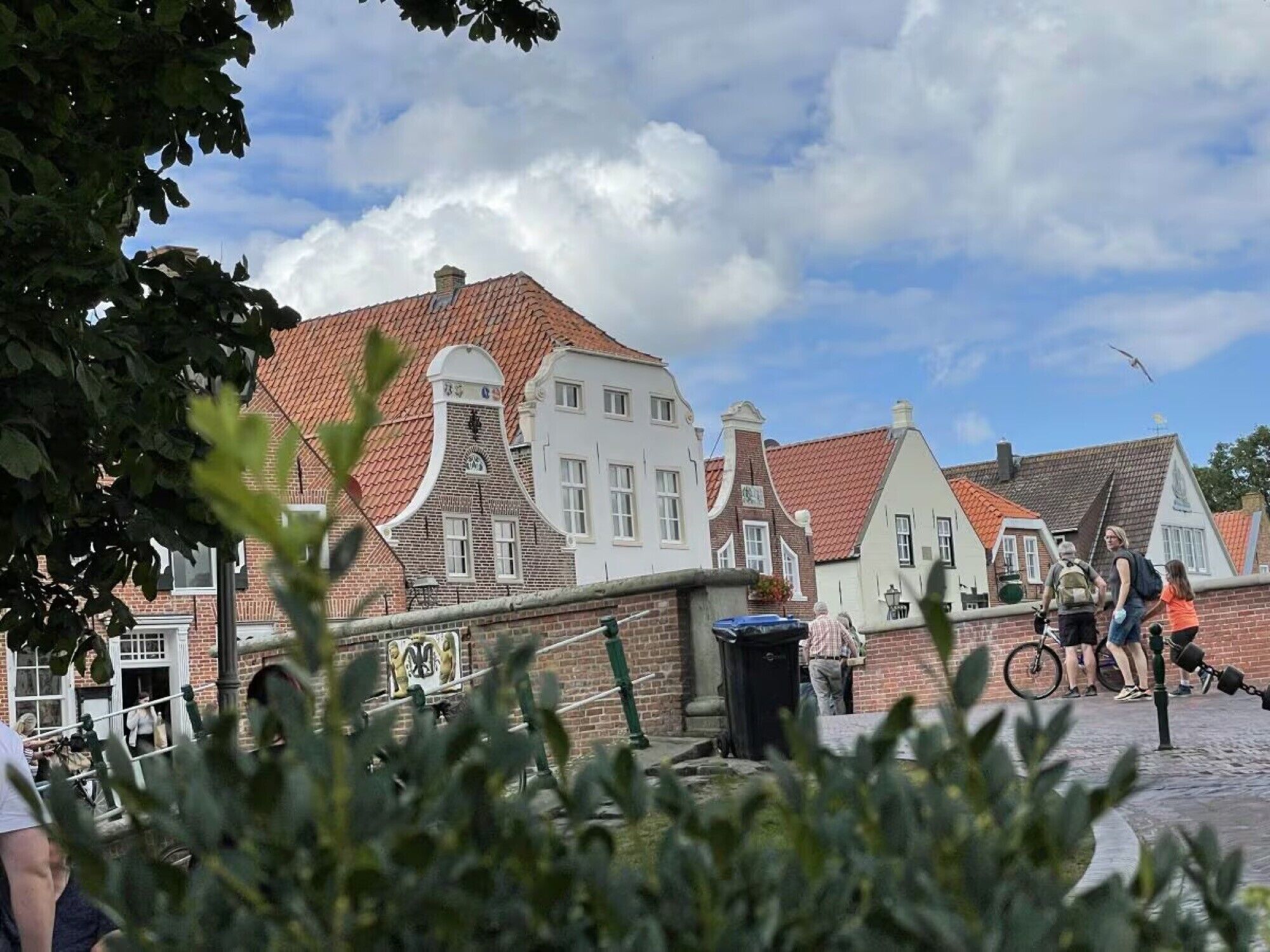 A traditional European street with brick buildings, a cobblestone path, and a clear sky.