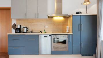 Une cuisine moderne avec des meubles gris, un lave-vaisselle, une cuisinière et une machine à café.