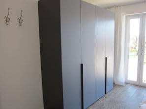 Ein Zimmer mit einem großen Kleiderschrank, einer Schiebetür aus Glas und einem kleinen dekorativen Gegenstand an der Wand.