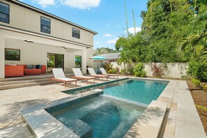 Ein modernes Haus mit Swimmingpool, Sitzgelegenheiten im Freien und einem gepflegten Garten.