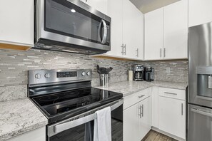A modern kitchen with stainless steel appliances, white cabinets, and a tiled backsplash. - Mins to Beaches/ Downtown, Heated Pool, Arlington Park (Sarasota)