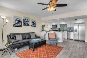 Un salon moderne avec un canapé en cuir noir, une table basse et un ventilateur de plafond.